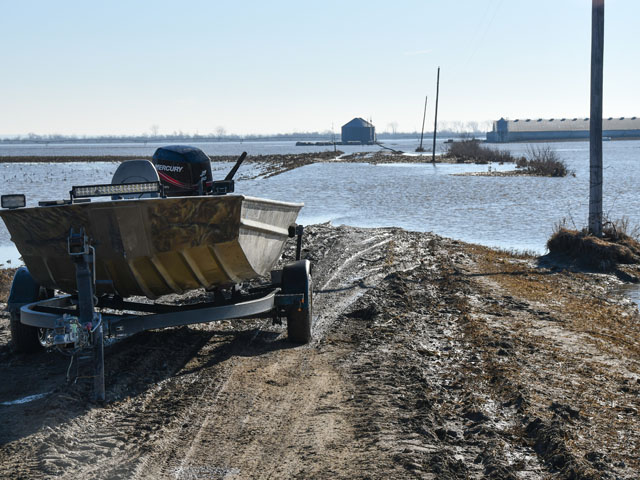 A motorboat sits ready to reach a hog building surrounded by Missouri River flood waters east of Herman, Nebraska. The hog building was not flooded, as it was built up higher, but the lane leading to the building was underwater. (DTN photo by Russ Quinn)